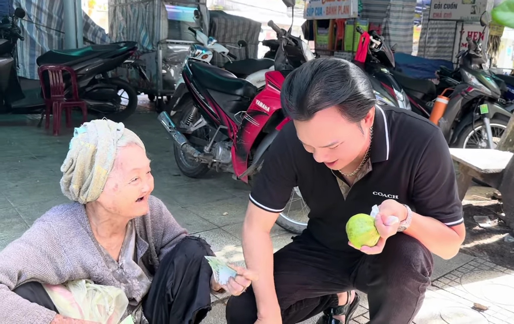 NSƯT Kim Tiểu Long cùng ê-kíp mua ủng hộ trái cây bà cụ bán